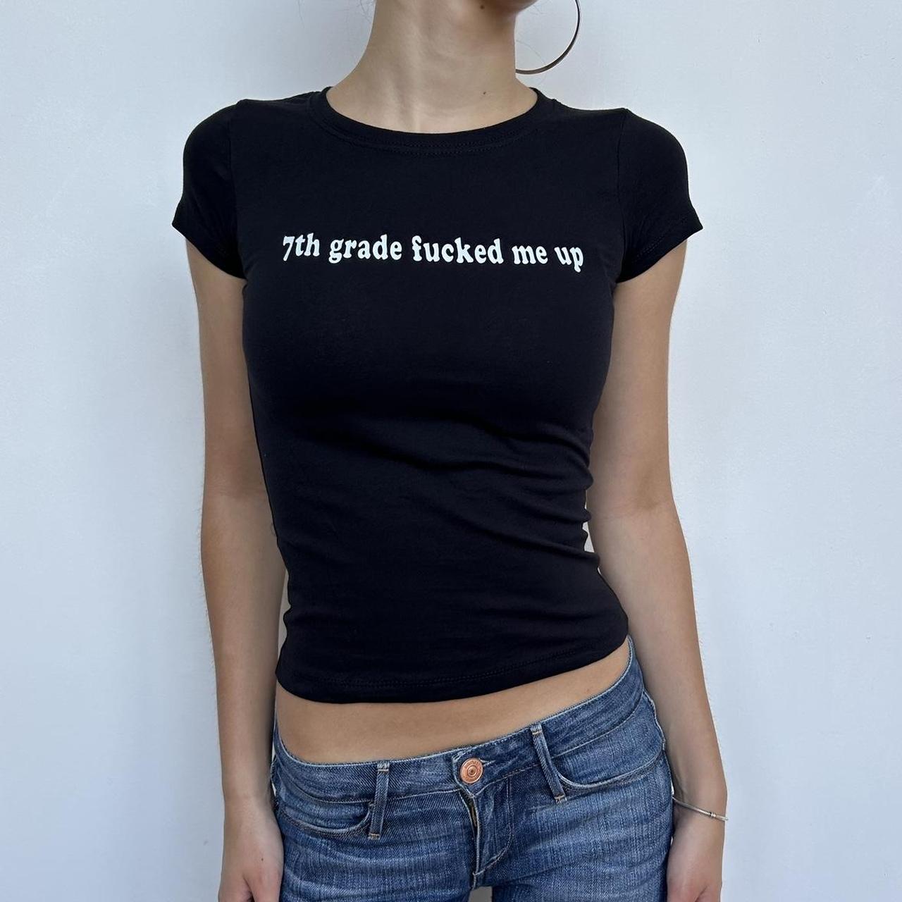 Model wearing black baby tee with "7th Grade Fucked Me Up" written in white across the chest.