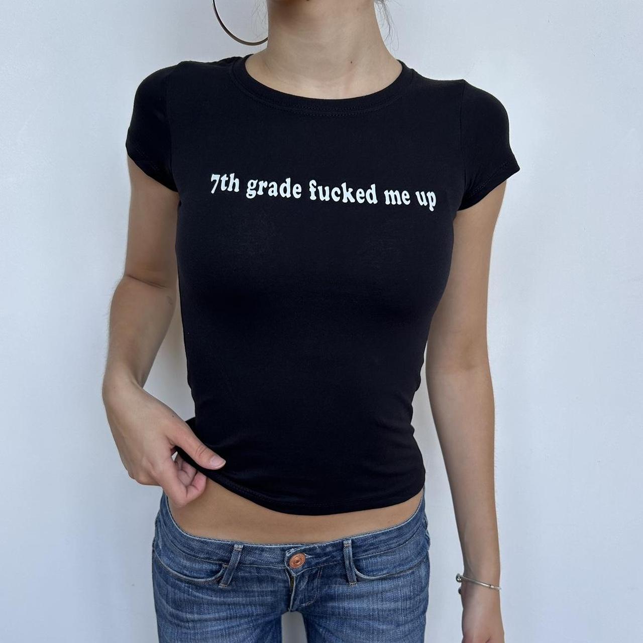 Model wearing black baby tee with "7th Grade Fucked Me Up" written in white across the chest.