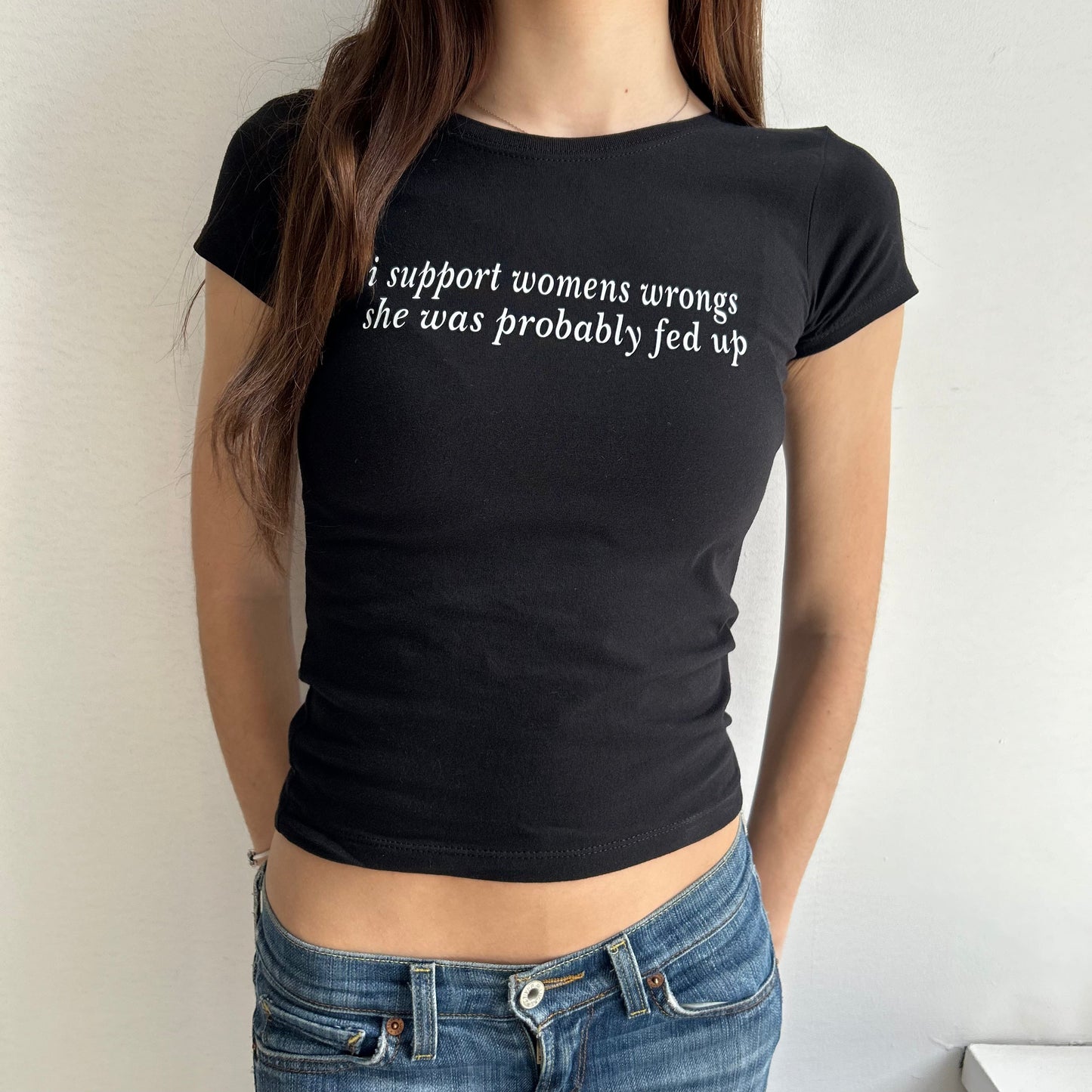 Model wearing black baby tee with "I support women's wrongs, she was probably fed up" written in white across the chest.