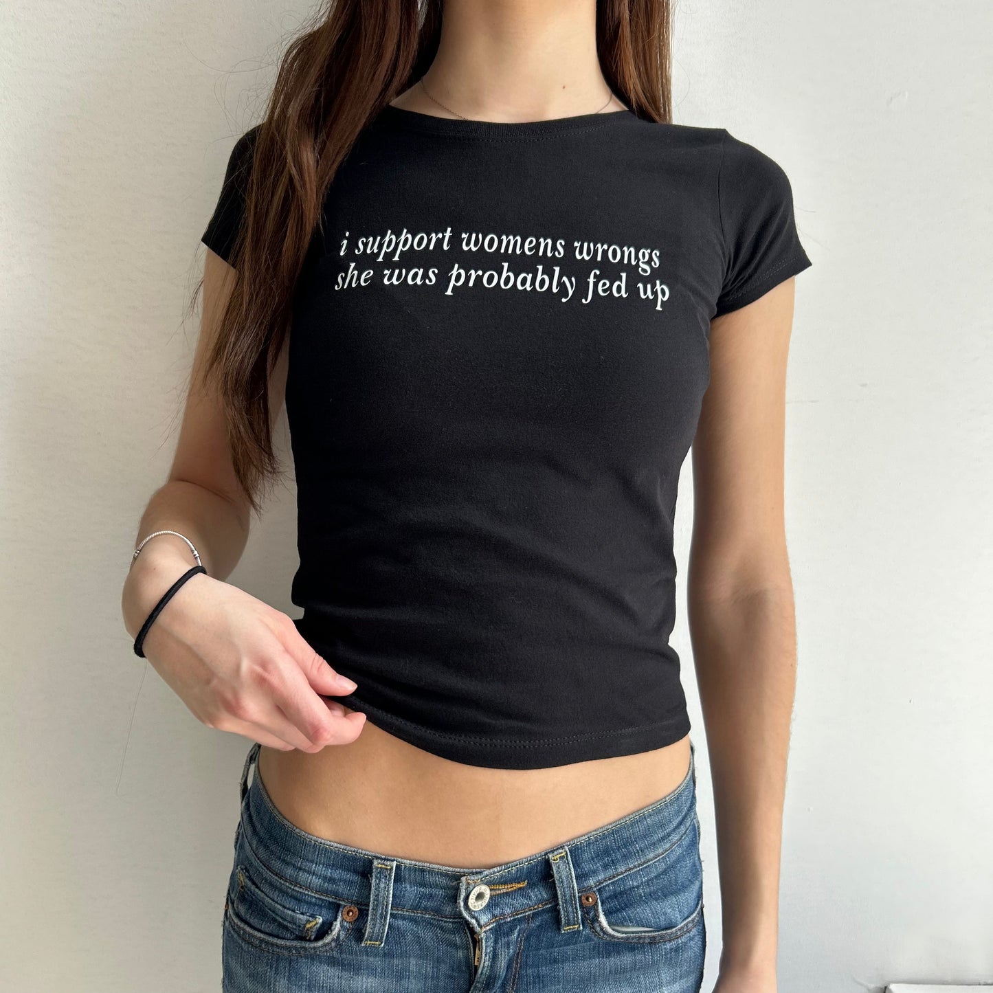 Model wearing black baby tee with "I support women's wrongs, she was probably fed up" written in white across the chest.