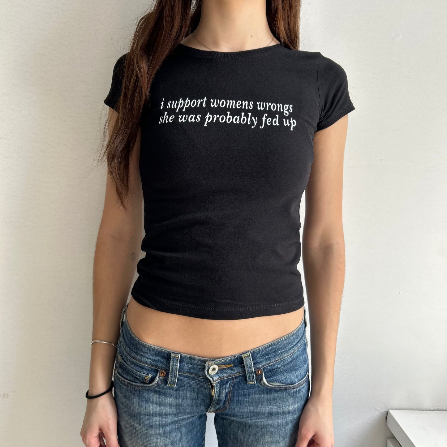 Model wearing black baby tee with "I support women's wrongs, she was probably fed up" written in white across the chest.