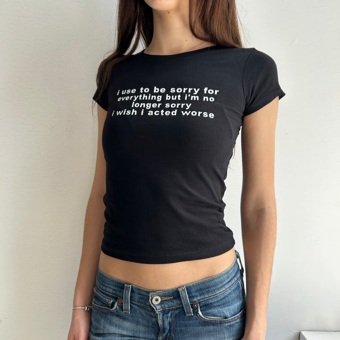 Model wearing black baby tee with "I Use To Be Sorry For Everything but I'm No Longer Sorry, I Wish I Acted Worse" written in white across the chest.