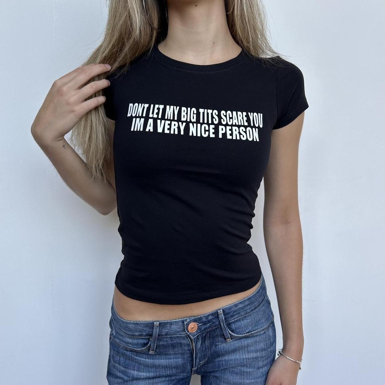 Model wearing black baby tee with "Don't Let My Big Tits Scare You, I'm A Very Nice Person" written in white across the chest.