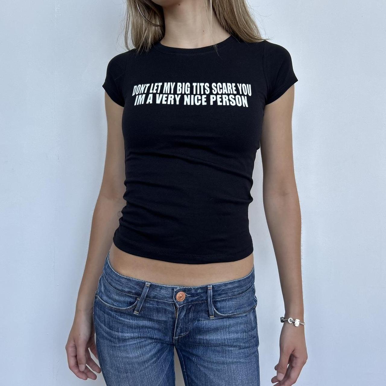 Model wearing black baby tee with "Don't Let My Big Tits Scare You, I'm A Very Nice Person" written in white across the chest.