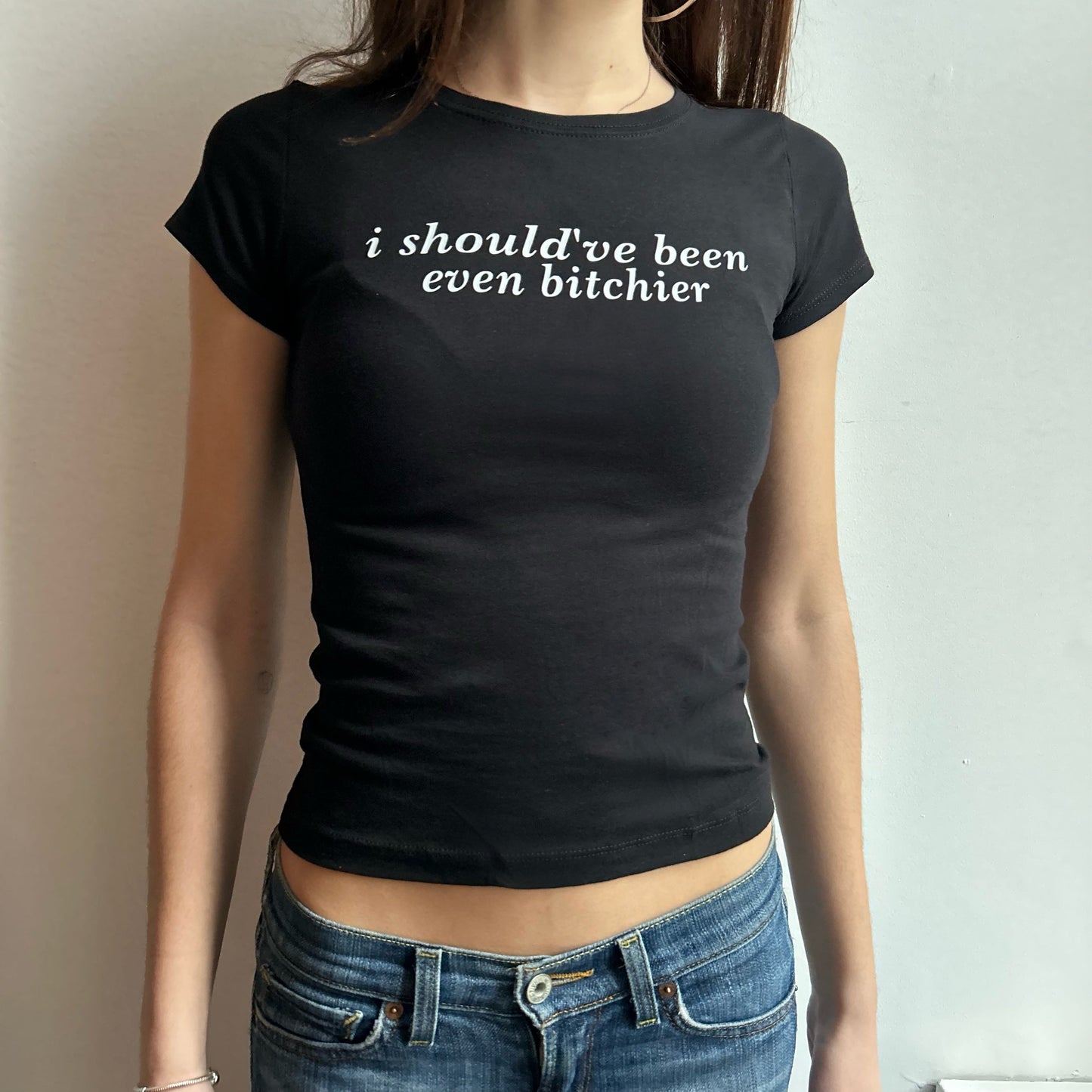 Model wearing black baby tee with "Should've Been Even Bitchier" written in white across the chest.