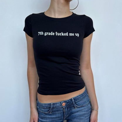 Model wearing black baby tee with "7th Grade Fucked Me Up" written in white across the chest.