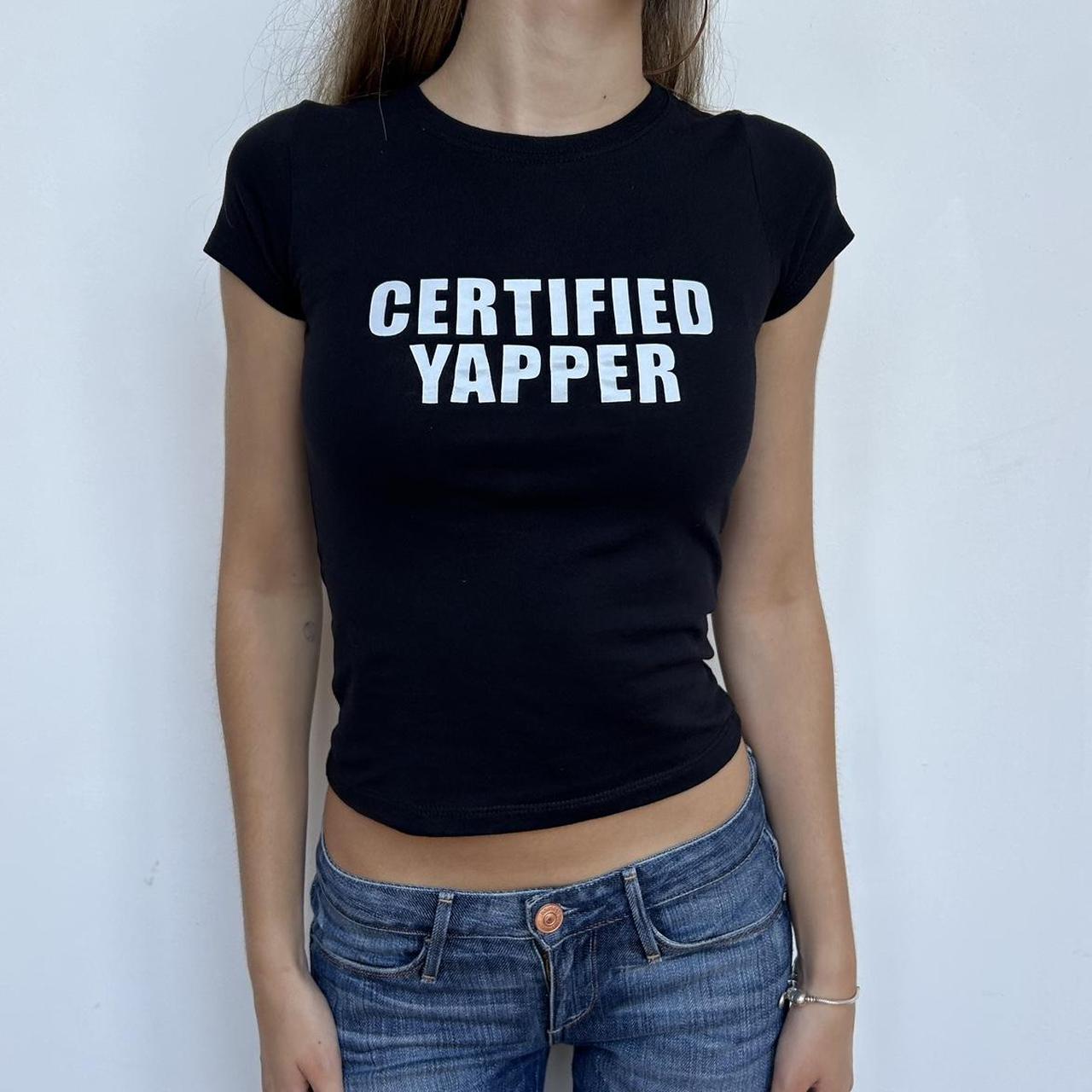 Model wearing black baby tee with "Certified Yapper Top" written in white across the chest.