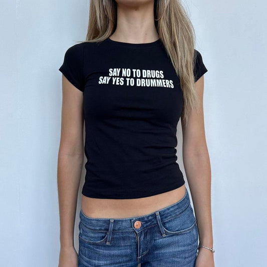 Model wearing black baby tee with "Say No to Drugs Say Yes to Drummers" written in white across the chest.