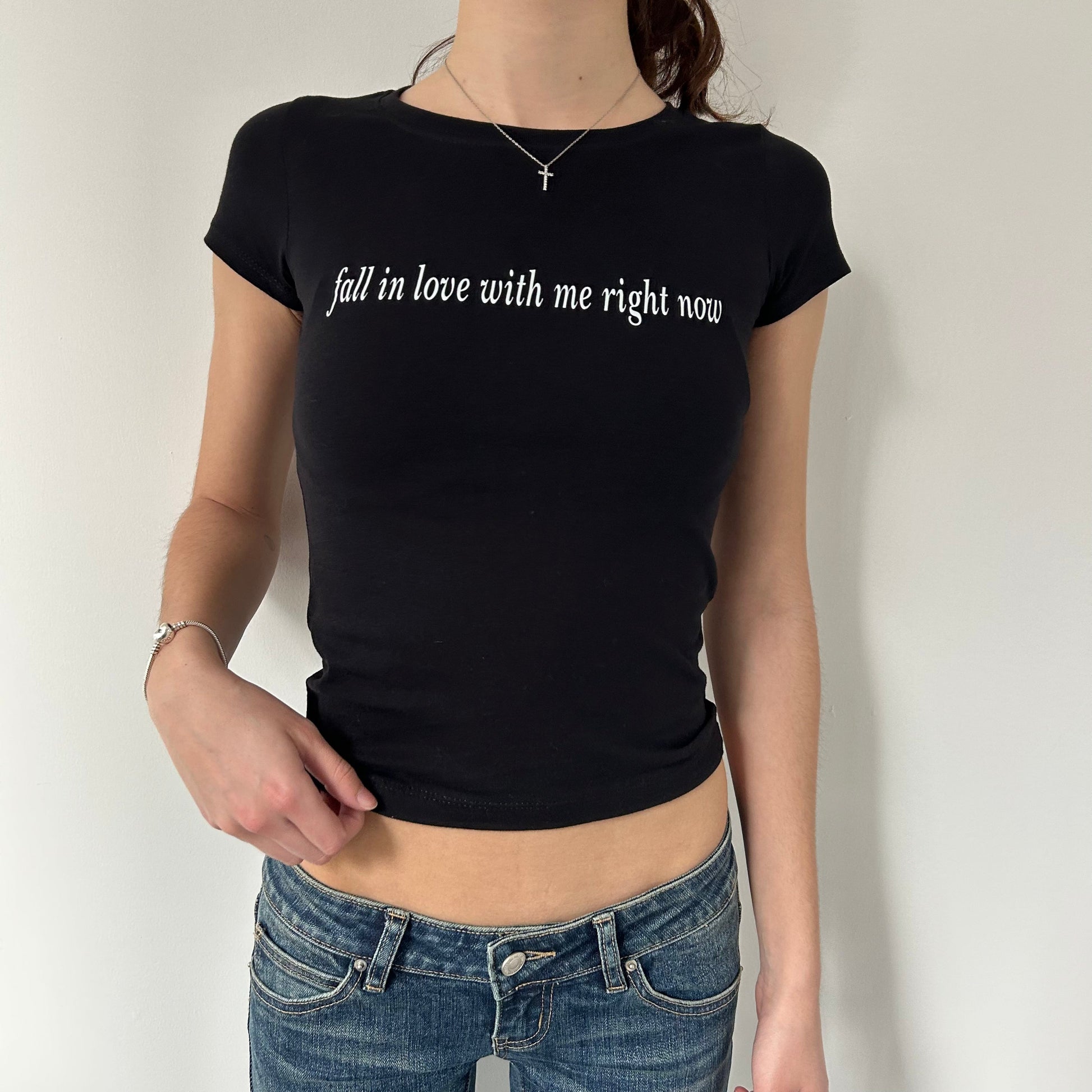 Model wearing black baby tee with "Fall in Love With Me Right Now" written in white across the chest.