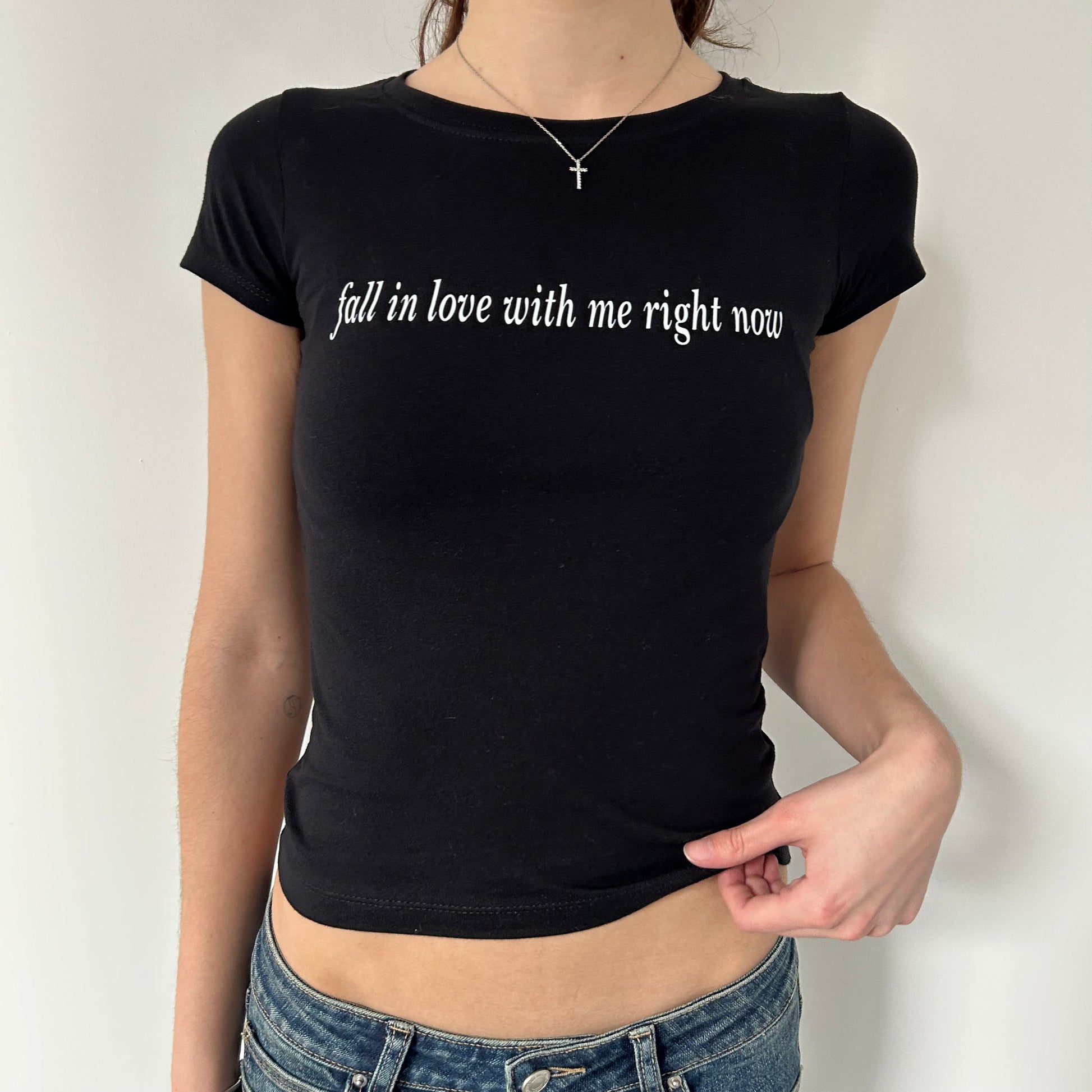Model wearing black baby tee with "Fall in Love With Me Right Now" written in white across the chest.