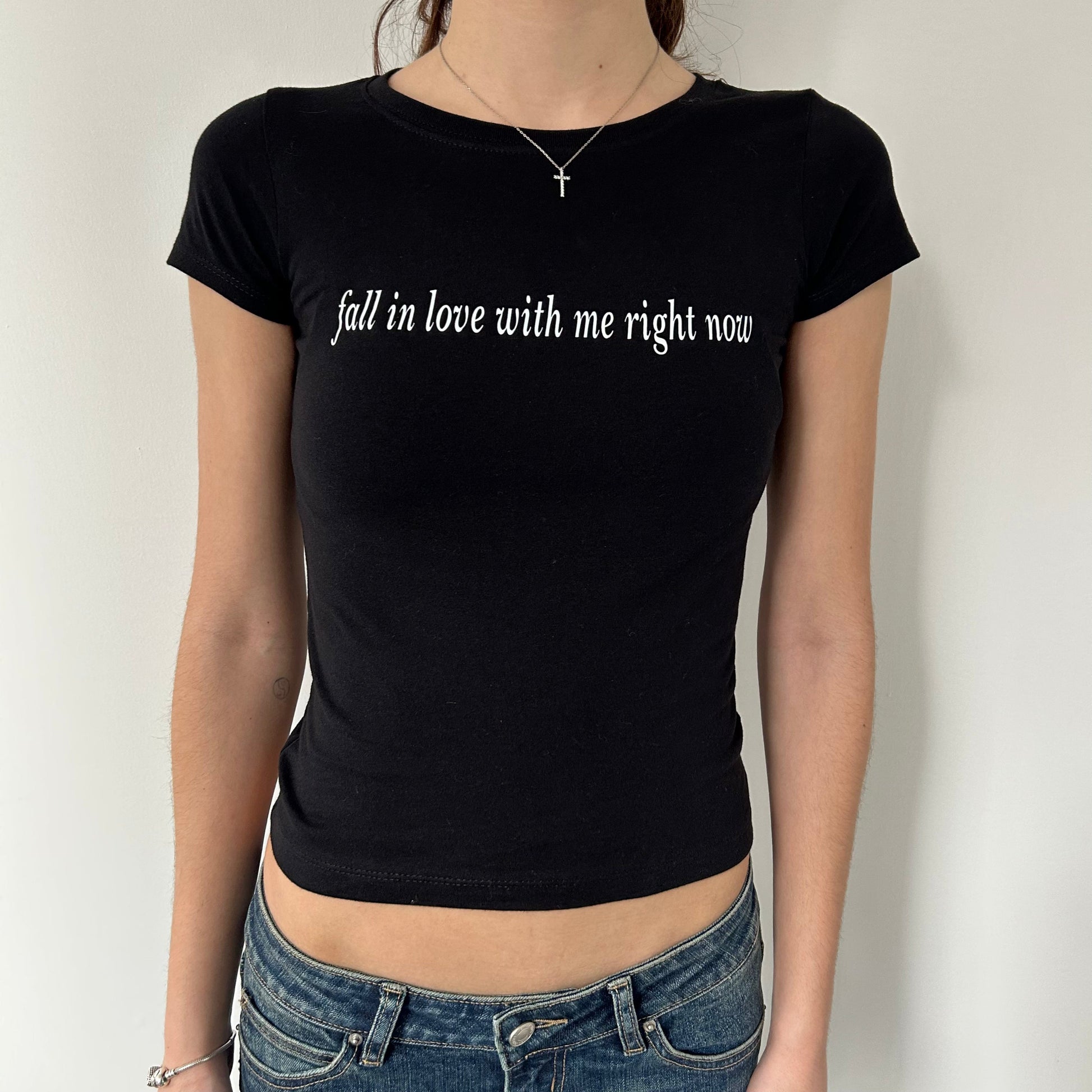 Model wearing black baby tee with "Fall in Love With Me Right Now" written in white across the chest.