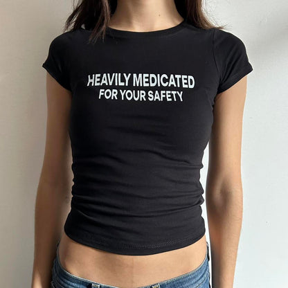 Model wearing black baby tee with "Heavily Medicated For Your Safety" written in white across the chest.