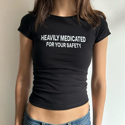 Model wearing black baby tee with "Heavily Medicated For Your Safety" written in white across the chest.