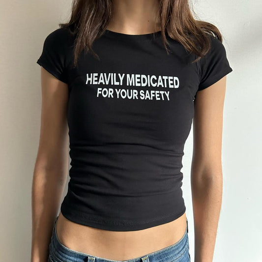Model wearing black baby tee with "Heavily Medicated For Your Safety" written in white across the chest.