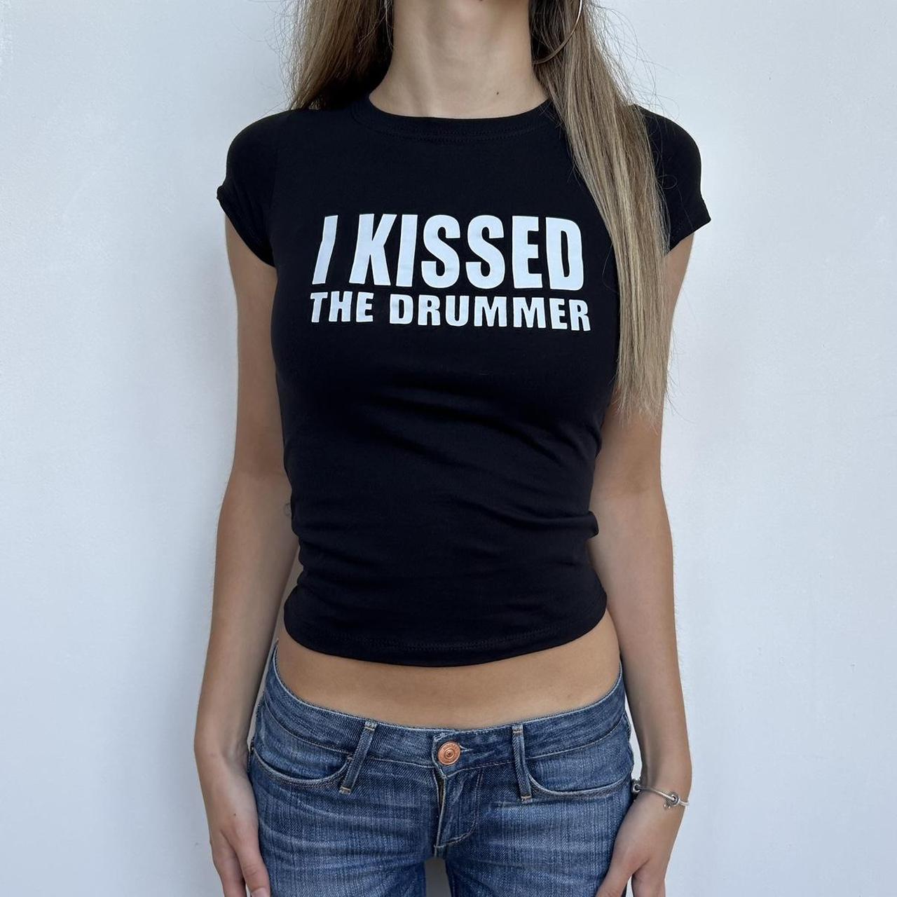 Model wearing black baby tee with "I Kissed The Drummer" written in white across the chest.