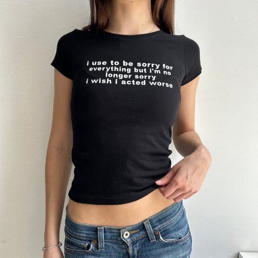Model wearing black baby tee with "I Use To Be Sorry For Everything but I'm No Longer Sorry, I Wish I Acted Worse" written in white across the chest.