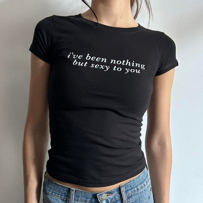 Model wearing black baby tee with "I've Been Nothing But Sexy To You" written in white across the chest.