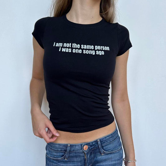 Model wearing black baby tee with "I Am Not The Same Person I Was One Song Ago" written in white across the chest.