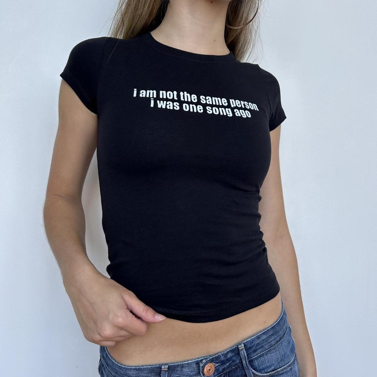 Model wearing black baby tee with "I Am Not The Same Person I Was One Song Ago" written in white across the chest.