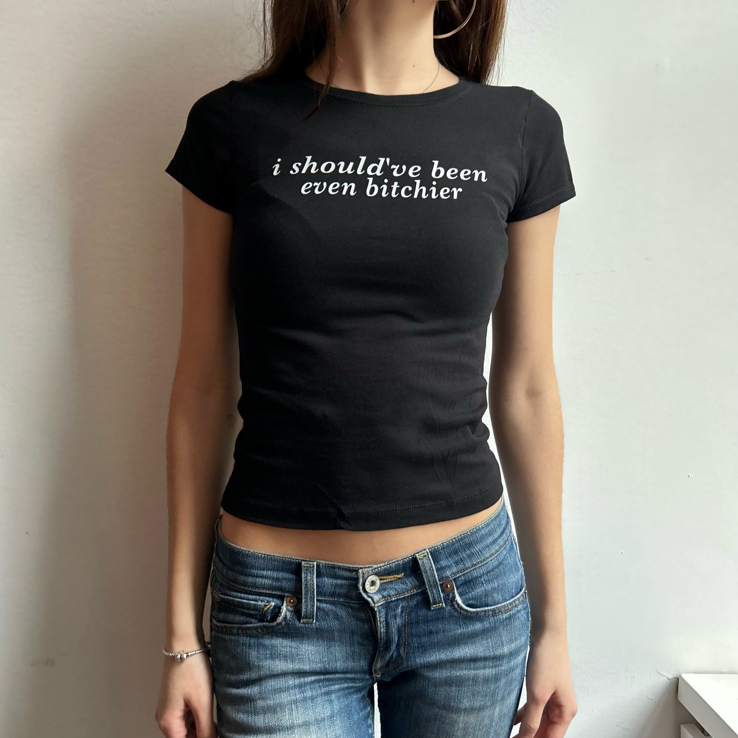 Model wearing black baby tee with "Should've Been Even Bitchier" written in white across the chest.