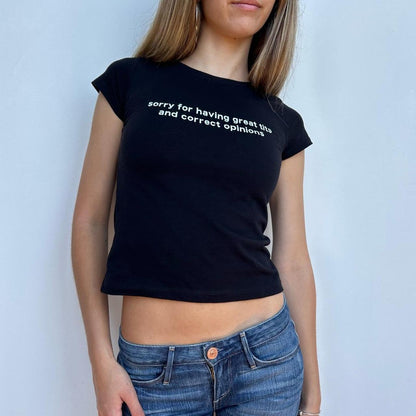 Model wearing black baby tee with "Sorry for Having Great Tits and Correct Opinions" written in white across the chest.