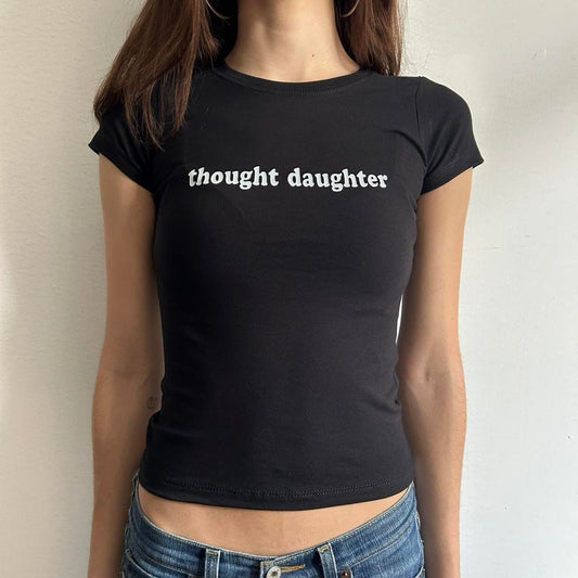 Model wearing black baby tee with "Thought Daughter" written in white across the chest.