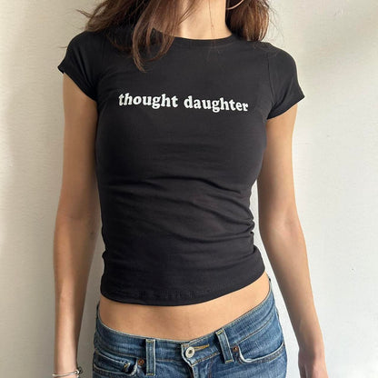 Model wearing black baby tee with "Thought Daughter" written in white across the chest.