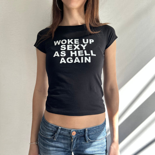 Model wearing black baby tee with "Woke Up Sexy As Hell" written in white across the chest.